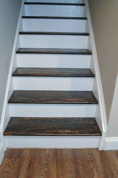 a set of wooden stairs leading up to a white wall