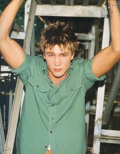 a young man holding his hands up to his head while standing in front of a metal structure