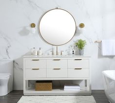 a white bathroom with marble counter tops and gold accents on the mirror above the sink