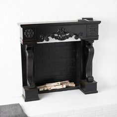 a black fireplace surround with wood logs