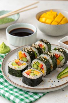 sushi is served on a plate with dipping sauce