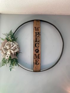 a welcome sign hanging on the wall next to a wreath