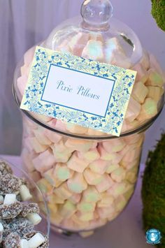 there is a glass jar filled with candy and marshmallows on the table