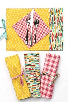 napkins, forks and spoons are laid out on a yellow tablecloth with colorful patterns