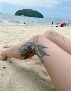 a woman's legs with tattoos on the beach