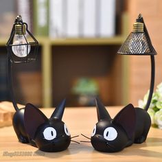 two black cat lamps sitting on top of a wooden table