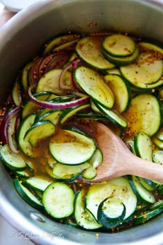 cooked zucchini and red onions in a pot with a wooden spoon on the side