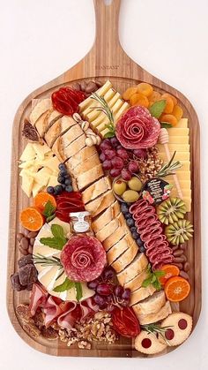 a wooden platter filled with assorted meats, cheeses and fruit slices