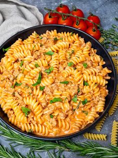 an easy ground turkey pasta recipe in a skillet with tomatoes and herbs on the side