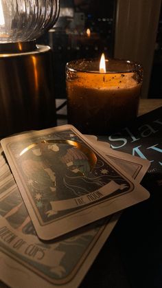 a candle and some cards on a table with candles in the backrounds