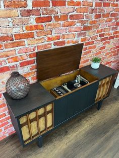 a sideboard with an open drawer on top and a brick wall in the background