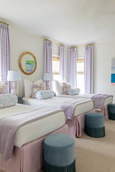 two beds in a room with purple and blue decor on the walls, along with stools