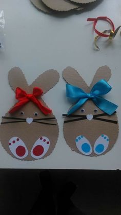 two paper bunny ears with blue and red bows on them sitting next to each other