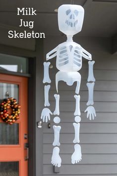 a skeleton hanging from the side of a house with text overlay that reads milk jug skeleton