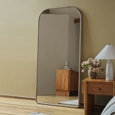 a large mirror sitting on top of a wooden table next to a lamp and dresser