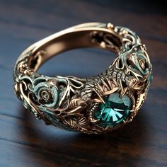 an ornate ring with a green stone in the center on a wooden surface, close up