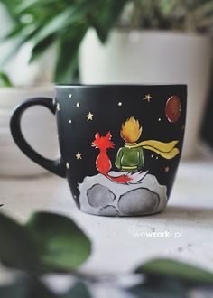 a black coffee cup with an image of a fox on it and stars in the sky