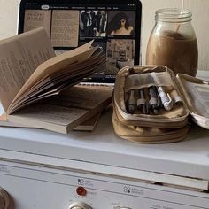 an open book sitting on top of a dryer in front of a laptop computer