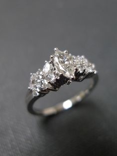 three stone diamond ring sitting on top of a black surface in front of a gray background