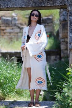 "This incredibly soft, breathable evil eye kaftan is the perfect cover-up for all your summer needs, from the beaches to picnics in the park. Made from 100% organic cotton and hand-printed with the timeless evil eye design, this Greek goddess-style kaftan will keep you protected from evil spirits and evil eyes. This kaftan is perfect for relaxing or dressing up with the ultimate ease of comfort. You can wear it around the house, on the beach, or dress it up with jeans and a T-shirt. Soft, light, and eco-friendly, it dries quickly and absorbs water better than a towel. Purpose of usage; Turkish cotton robe, spa bath, boho robe, Made of %100 Cotton, Ethnic Kaftan, Kimono Robe, Dressing gown, Boho Cover Up, Meditation Robe, Organic Cotton bathrobe, lithograph pattern, Unisex Spa robe Dries ve Bohemian White Robe For Festivals, White Boho Print Kimono For Festival, Bohemian Robe With Kimono Sleeves For Festivals, Hippie Long Sleeve Robe For Festivals, Hippie Long Sleeve Festival Robe, Printed Long Sleeve Festival Robe, Hippie Festival Robe With Kimono Sleeves, Hippie Long Robe For Vacation, Long Hippie Robe For Vacation