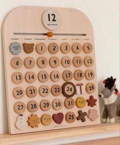 a wooden calendar sitting on top of a shelf next to a toy horse and stuffed animal