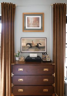 a dresser with drawers and pictures on the wall