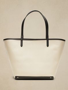 An elegant companion to everyday style, this classic tote goes anywhere with ease with spacious storage, sturdy leather trim, and a snap closure.  Sturdy leather handles.  Open top with snap closure.  Height: 16" (41cm) Width: 25" (63cm) Depth: 8" (2 Coated Canvas Bucket Bag For Shopping, Chic Coated Canvas Bucket Bag For Shopping, Classic Coated Canvas Bag For Errands, Everyday Bucket Bag With Double Leather Handles, Classic Shoulder Bag With Snap Closure For Errands, Coated Canvas Tote Bucket Bag, Everyday Canvas Bucket Bag With Leather Trim, Coated Canvas Bucket Bag Tote For Errands, Elegant Coated Canvas Bucket Bag For Errands