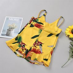 two pieces of yellow floral print swimsuits next to a sunflower and magazine