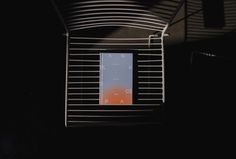 an orange and blue book sitting on top of a metal shelf next to a window