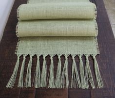 three pieces of fabric with fringes on a wooden table