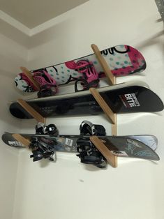 three snowboards mounted to the side of a wall with skis on top of them