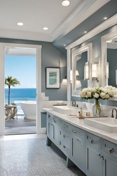 a large bathroom with two sinks and a bathtub in front of the window overlooking the ocean