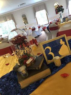 a table topped with books and vases filled with flowers next to a cake on top of a book