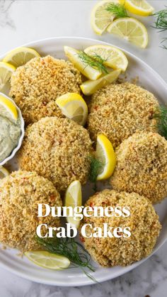 a white plate topped with crab cakes and lemon wedges