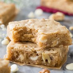 three pieces of cookie bars stacked on top of each other with nuts scattered around them