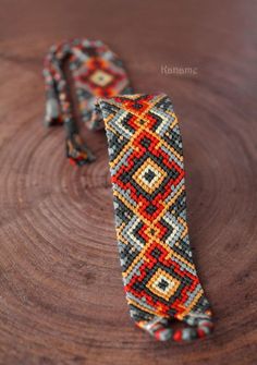 an orange and black tie sitting on top of a wooden table next to a piece of wood