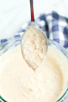 a spoon full of dip in a glass bowl with a blue and white checkered napkin