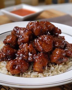 a white plate topped with rice covered in sauce and chicken wings on top of it