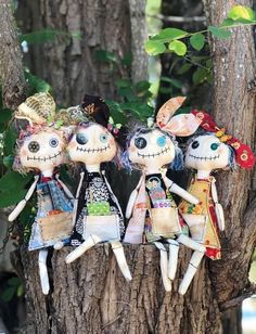 three little dolls sitting on top of a tree