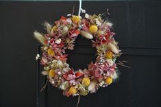 a wreath with dried flowers hanging on a door