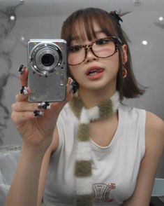 a woman taking a selfie in front of a mirror wearing glasses and holding a camera