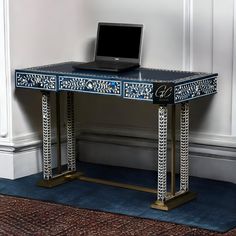 a laptop computer sitting on top of a blue and white desk next to a rug