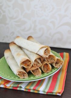 three burritos on a green plate sitting on a table