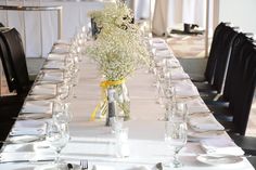 the table is set with white linens and baby's breath centerpieces