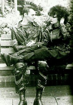 black and white photograph of two people sitting on a bench with their feet up against each other