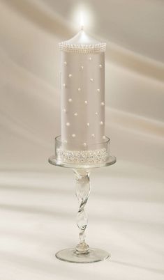 a candle that is sitting in a glass holder on a white tableclothed background