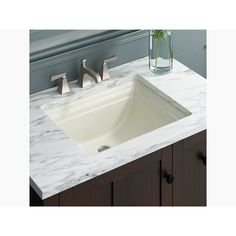 a white sink sitting on top of a counter next to a vase filled with flowers