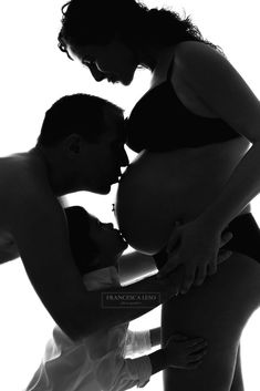 a man and woman kissing in front of a white background with their reflection on the ground