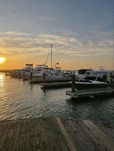 several boats are docked in the water at sunset