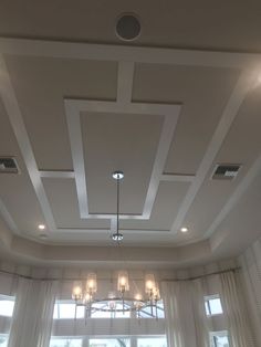 a living room filled with lots of furniture next to two large windows and a chandelier